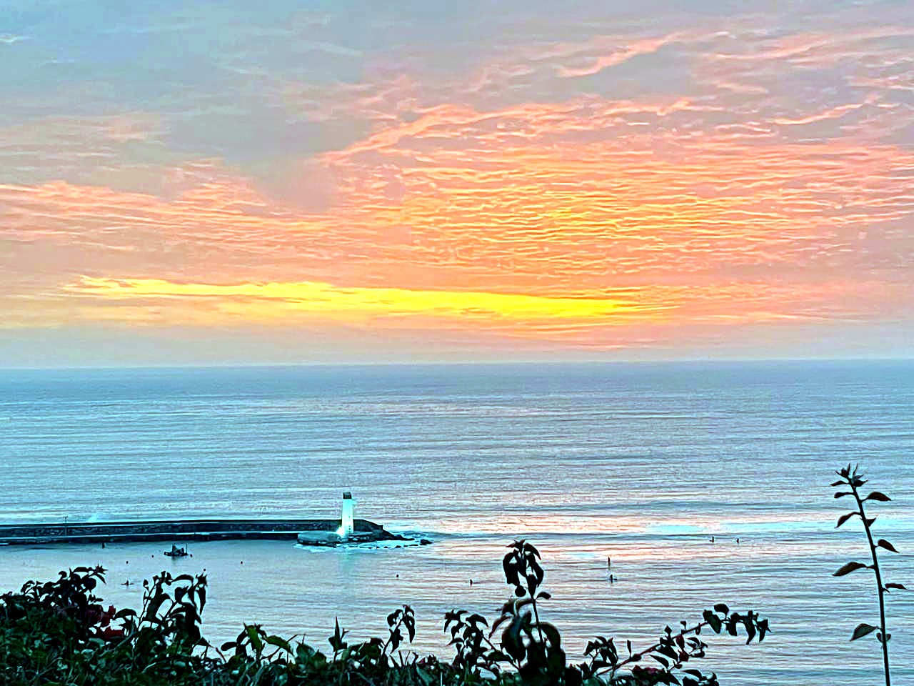灯台と太平洋に沈む鮮やかなオレンジ色の夕日
